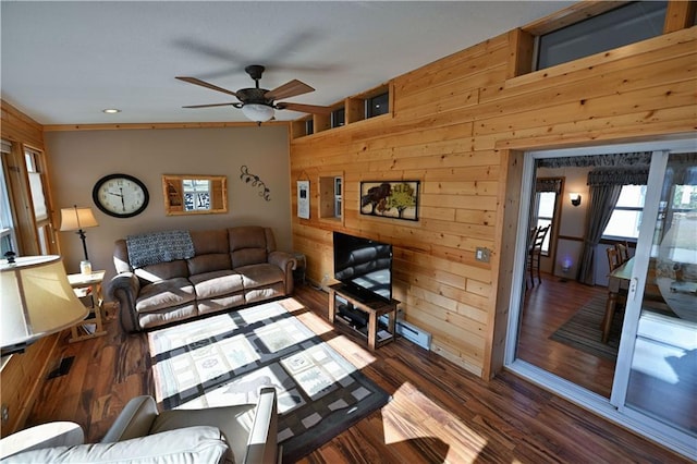 living room with wood walls, a ceiling fan, and wood finished floors