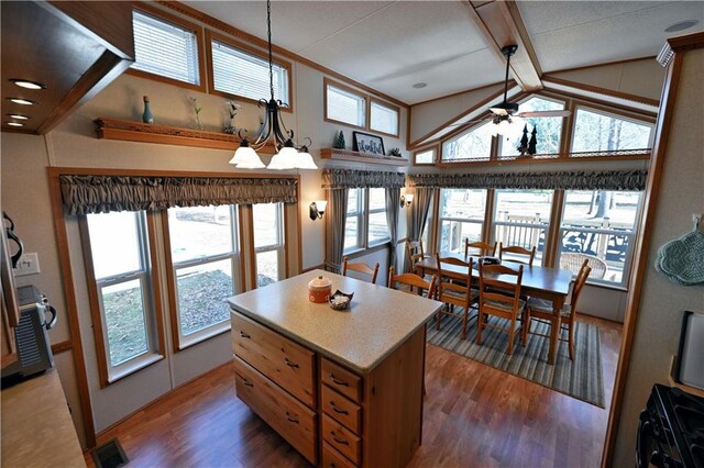 kitchen featuring hanging light fixtures, ceiling fan with notable chandelier, vaulted ceiling with beams, wood finished floors, and a kitchen island
