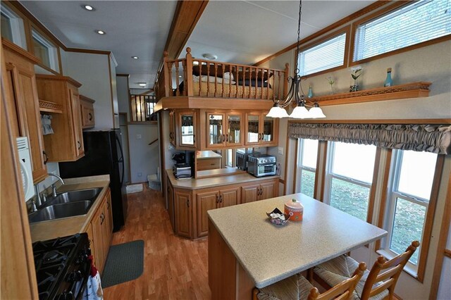 kitchen with a sink, light countertops, light wood-style flooring, a center island, and black appliances
