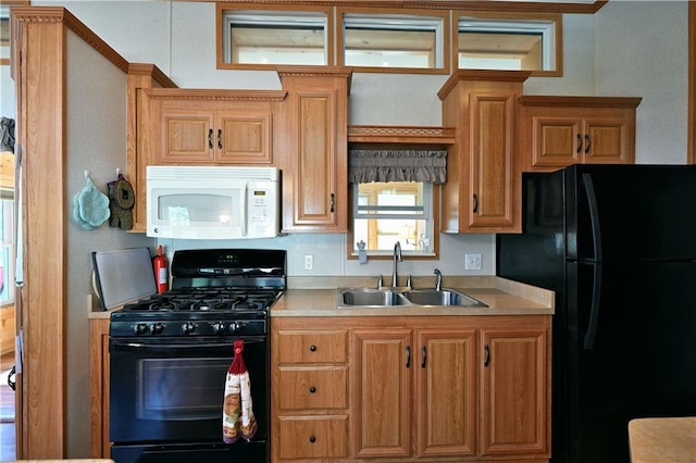 kitchen with a sink, light countertops, brown cabinetry, and black appliances