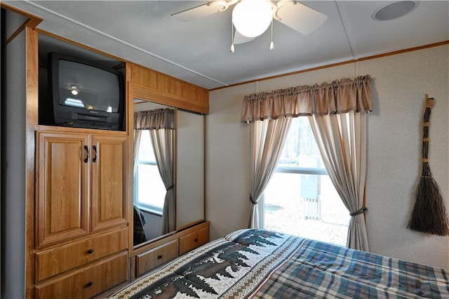 bedroom with crown molding, a ceiling fan, and multiple windows