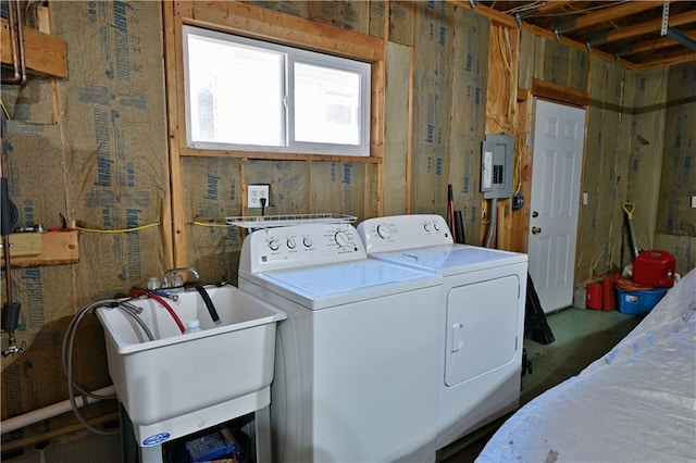 laundry area with laundry area, washing machine and dryer, a sink, and electric panel
