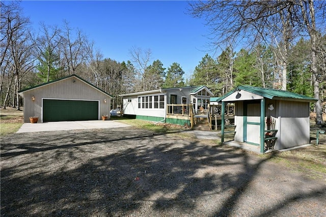 view of front facade featuring a detached garage, a deck, and an outbuilding