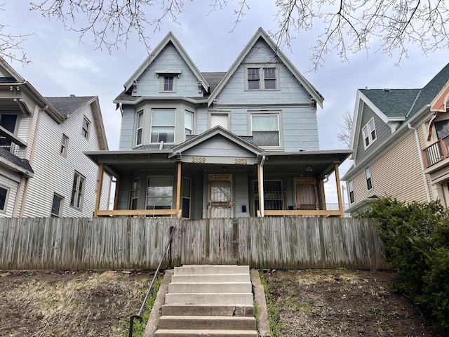 victorian-style house featuring fence and covered porch