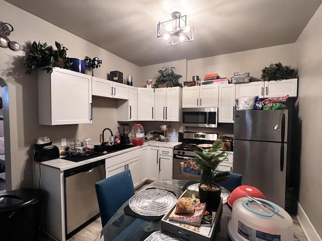 kitchen with light countertops, a sink, white cabinetry, and stainless steel appliances