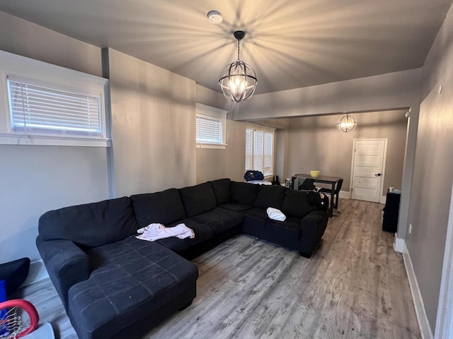 living room with baseboards, an inviting chandelier, and light wood-style flooring