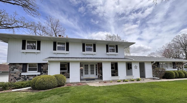 traditional home with french doors, stone siding, and a front lawn