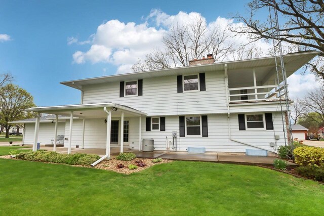 rear view of house featuring a patio, a chimney, a yard, and central AC unit