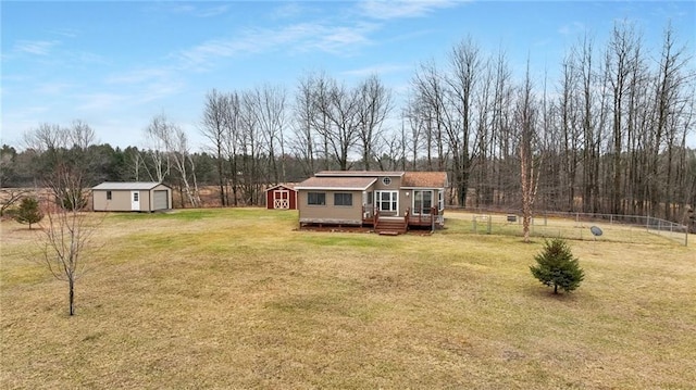 view of yard featuring an outdoor structure, a wooden deck, fence, and a garage