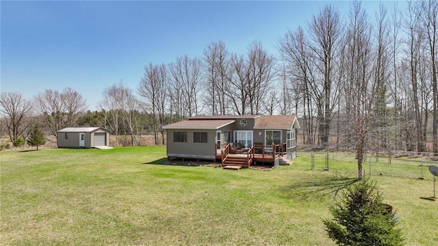 back of property with a yard, a detached garage, a wooden deck, and an outbuilding