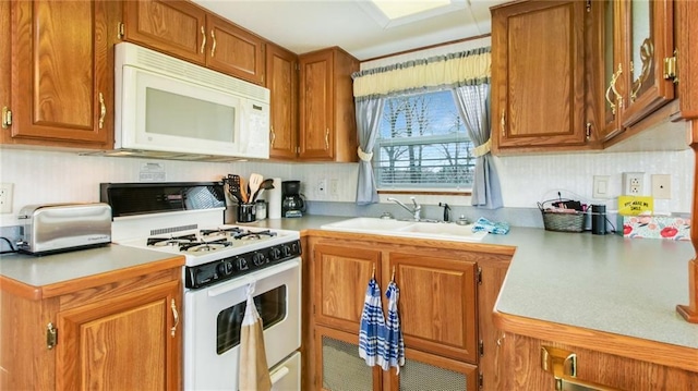 kitchen featuring brown cabinets, white appliances, light countertops, and a sink