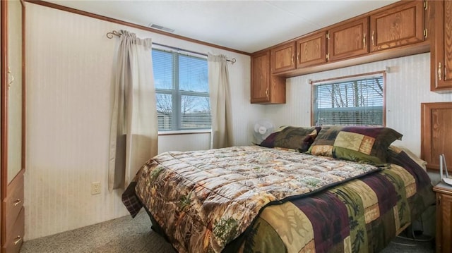 carpeted bedroom featuring multiple windows, crown molding, and visible vents