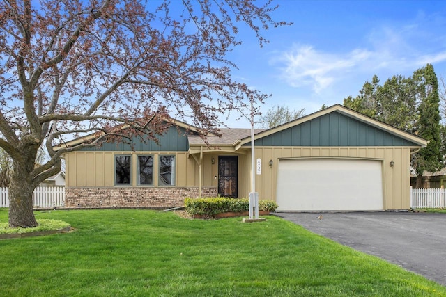 ranch-style house featuring an attached garage, fence, driveway, and a front yard