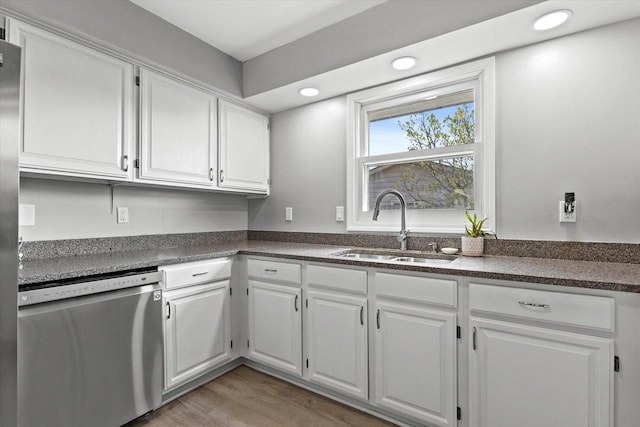 kitchen with a sink, white cabinetry, dishwasher, and dark countertops