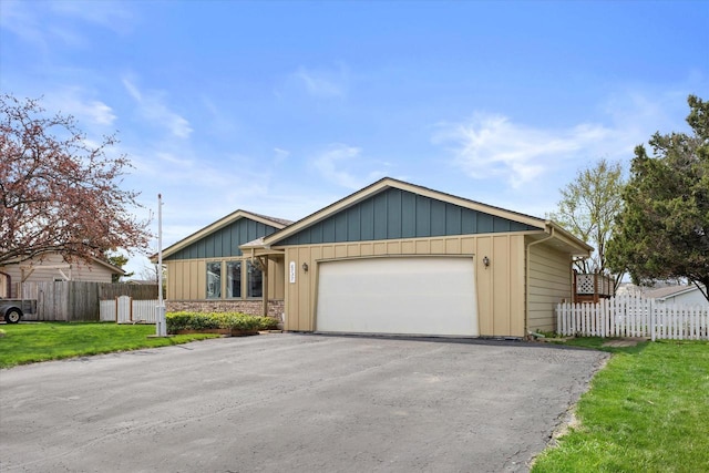 view of front of home with fence, driveway, a front yard, and a garage