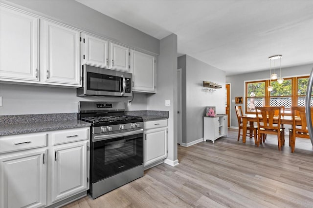 kitchen with decorative light fixtures, appliances with stainless steel finishes, light wood-type flooring, baseboards, and white cabinets