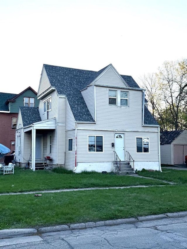view of front facade featuring entry steps, roof with shingles, and a front yard