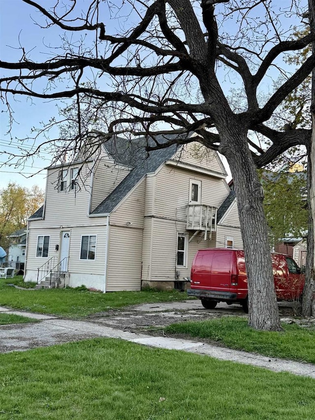 view of front of property with a shingled roof and a front yard