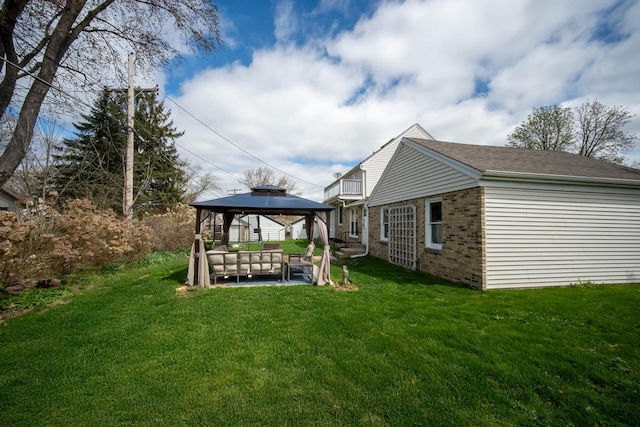 exterior space featuring a lawn, a gazebo, a patio area, and brick siding