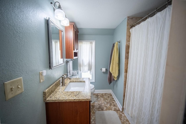 full bathroom featuring vanity, a textured wall, curtained shower, toilet, and baseboards