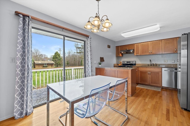 kitchen featuring brown cabinetry, light wood finished floors, under cabinet range hood, and stainless steel appliances