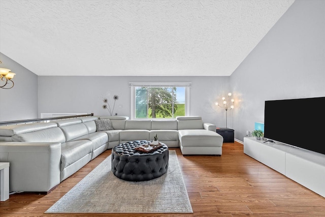 living area with an inviting chandelier, vaulted ceiling, a textured ceiling, and wood finished floors