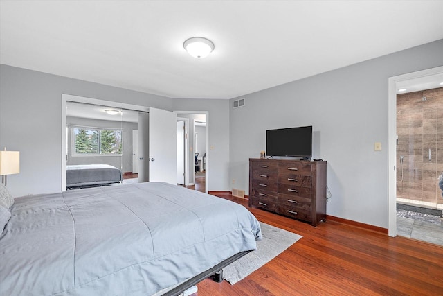 bedroom featuring visible vents, connected bathroom, baseboards, and wood finished floors