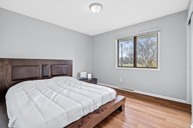 bedroom featuring baseboards, wood finished floors, and visible vents