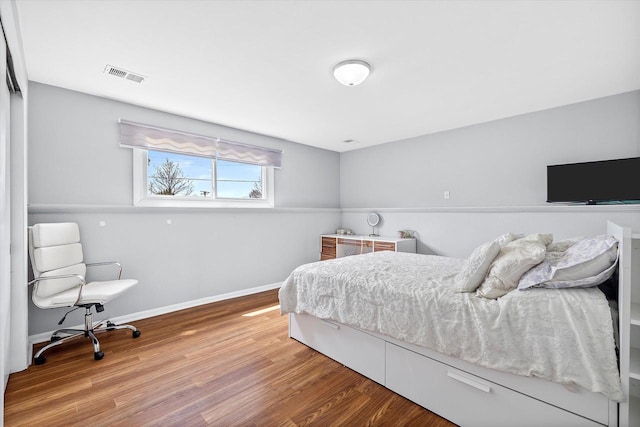 bedroom with visible vents, baseboards, and wood finished floors