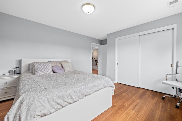 bedroom with a closet, wood finished floors, and visible vents