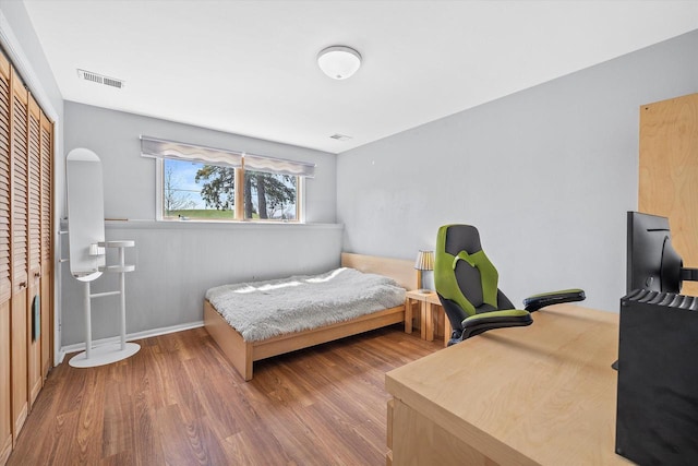 bedroom with visible vents, wood finished floors, and a closet