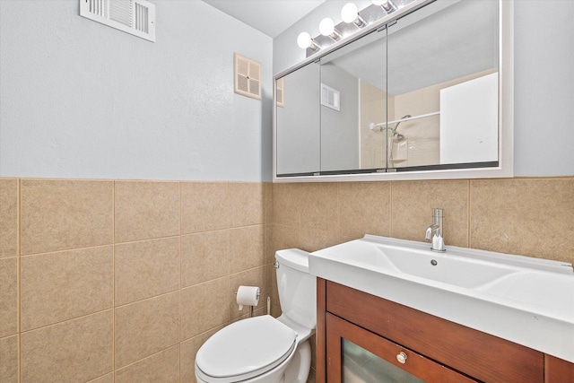 bathroom featuring toilet, visible vents, and tile walls