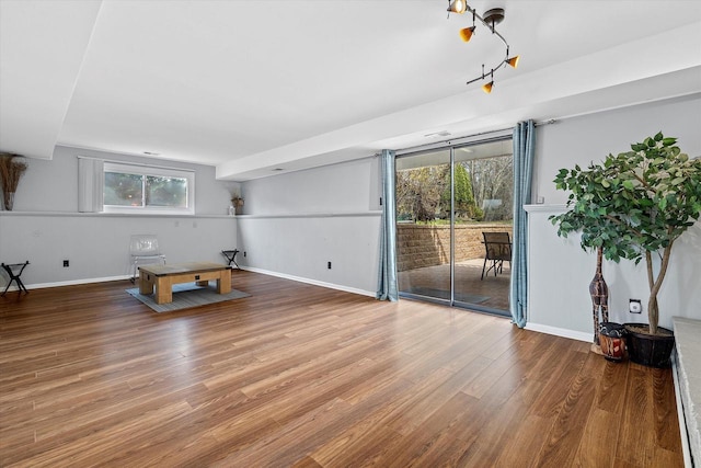 unfurnished living room featuring a healthy amount of sunlight, baseboards, and wood finished floors
