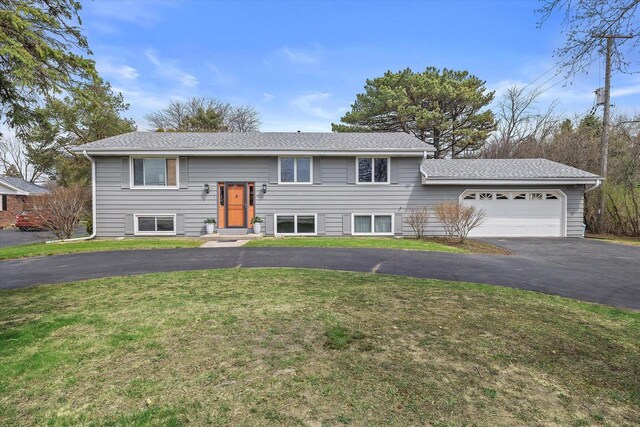 split foyer home featuring an attached garage, driveway, and a front lawn