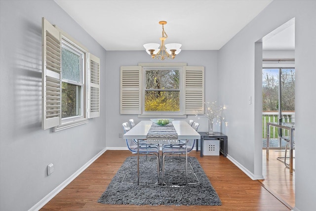 dining space featuring baseboards, wood finished floors, and a notable chandelier