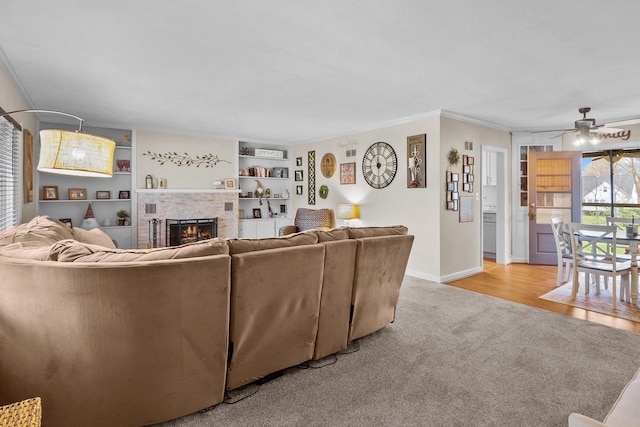 living room featuring crown molding, ceiling fan, light colored carpet, a fireplace, and built in features