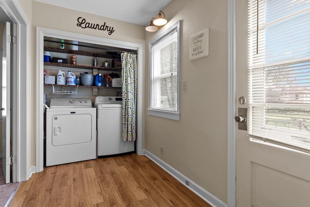 laundry room featuring baseboards, laundry area, light wood finished floors, and washer and clothes dryer