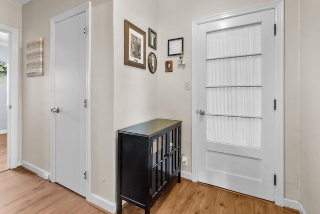 doorway with baseboards and wood finished floors