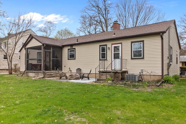 back of house with a sunroom, a lawn, central air condition unit, and a chimney