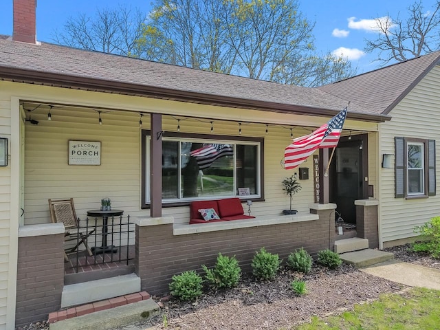 doorway to property with a porch, a shingled roof, and a chimney