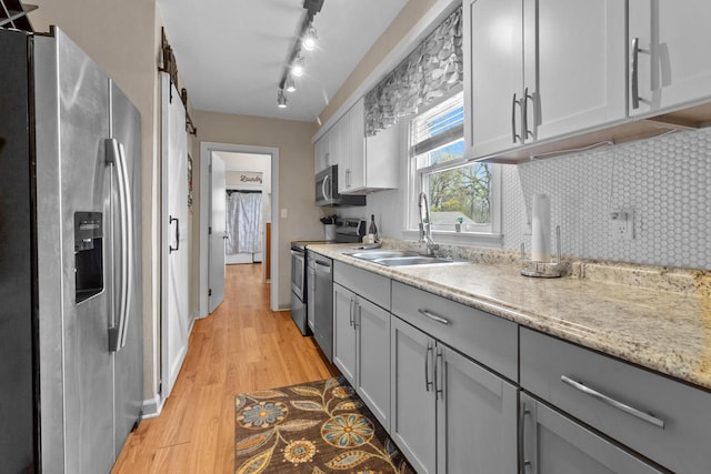 kitchen with a sink, light wood-style flooring, appliances with stainless steel finishes, and gray cabinetry