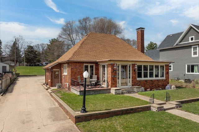 233 N 1st St, Princeton, WI 54968 - view of front facade featuring brick siding, a chimney, a front lawn, concrete driveway, and a shingled roof