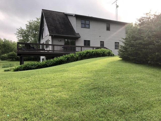 back of property featuring a lawn, a wooden deck, and a shingled roof