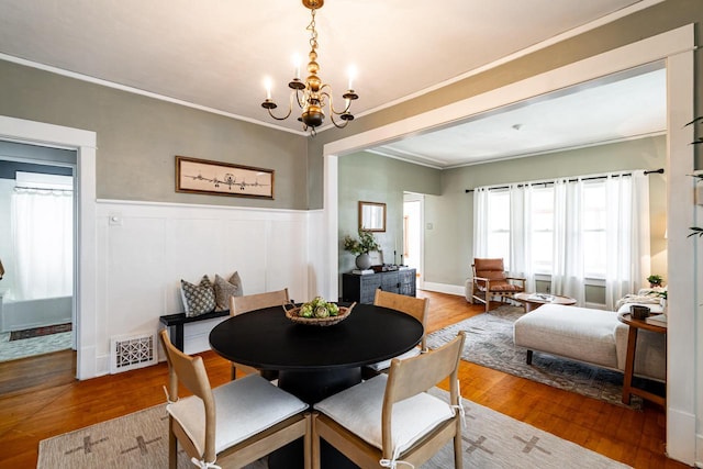 dining area featuring visible vents, ornamental molding, wood finished floors, and a notable chandelier