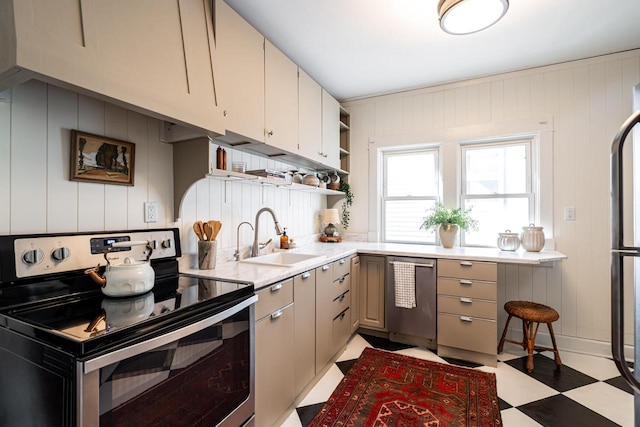 kitchen with open shelves, light stone countertops, light floors, a sink, and appliances with stainless steel finishes