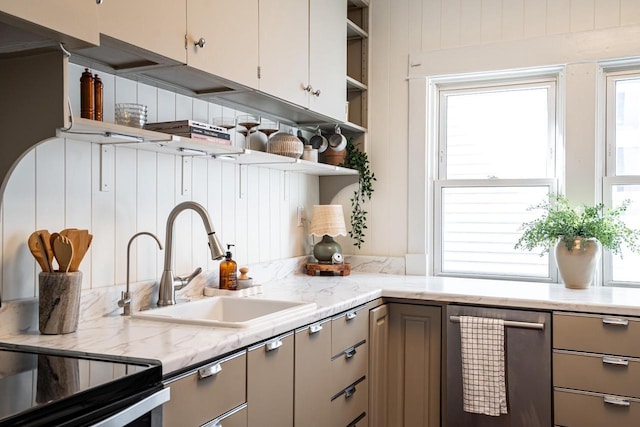 kitchen with stainless steel dishwasher, open shelves, light stone countertops, gray cabinets, and a sink
