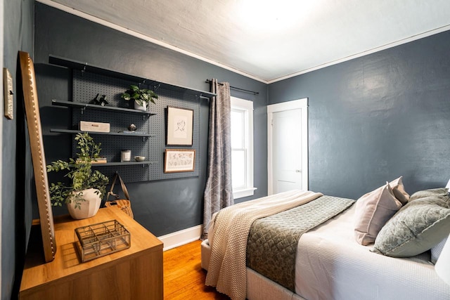 bedroom featuring baseboards, crown molding, and wood finished floors
