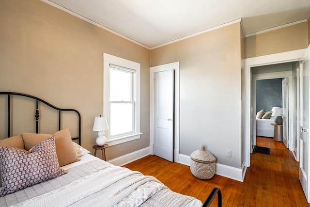 bedroom featuring a closet, baseboards, ornamental molding, and hardwood / wood-style floors