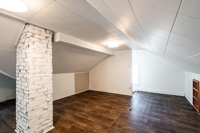 bonus room with dark wood-type flooring, vaulted ceiling, and visible vents