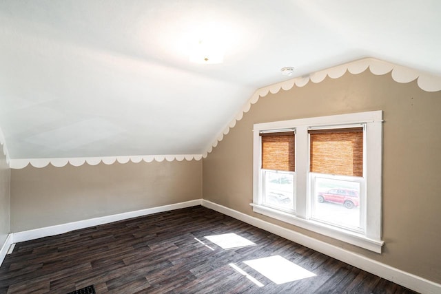 additional living space with baseboards, dark wood-style floors, and lofted ceiling